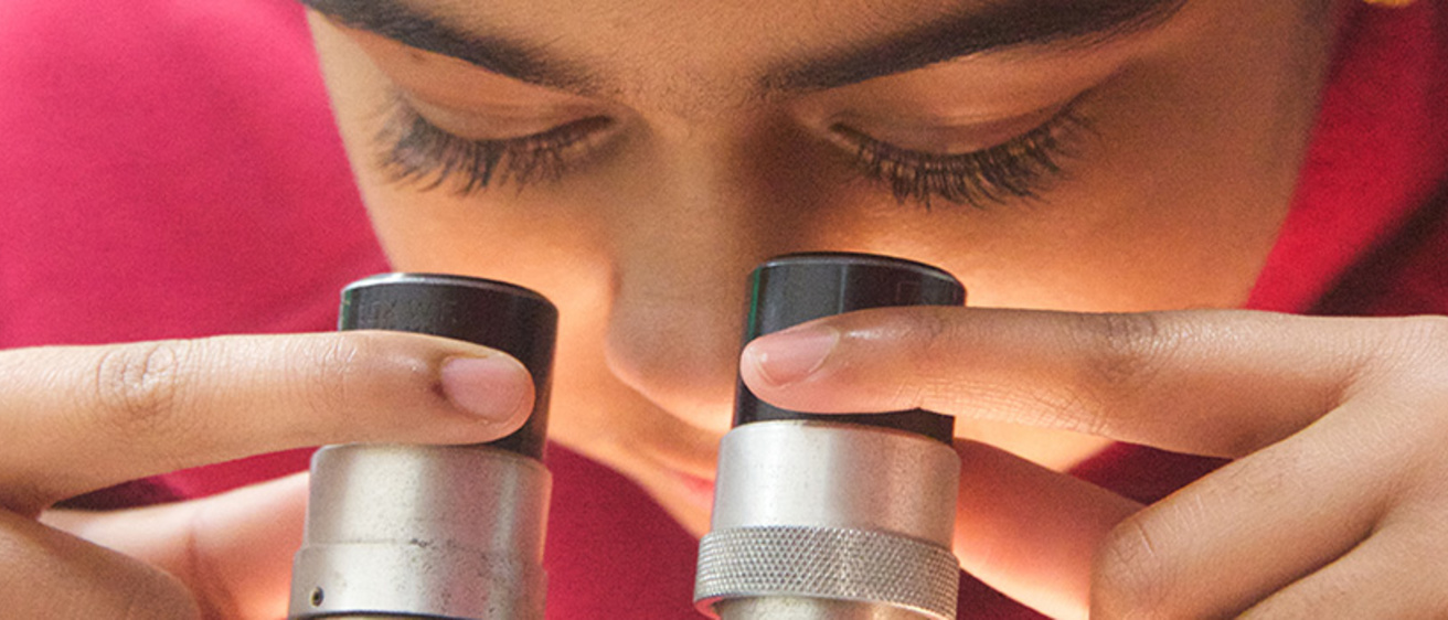 Close-up image of a child looking into a microscope